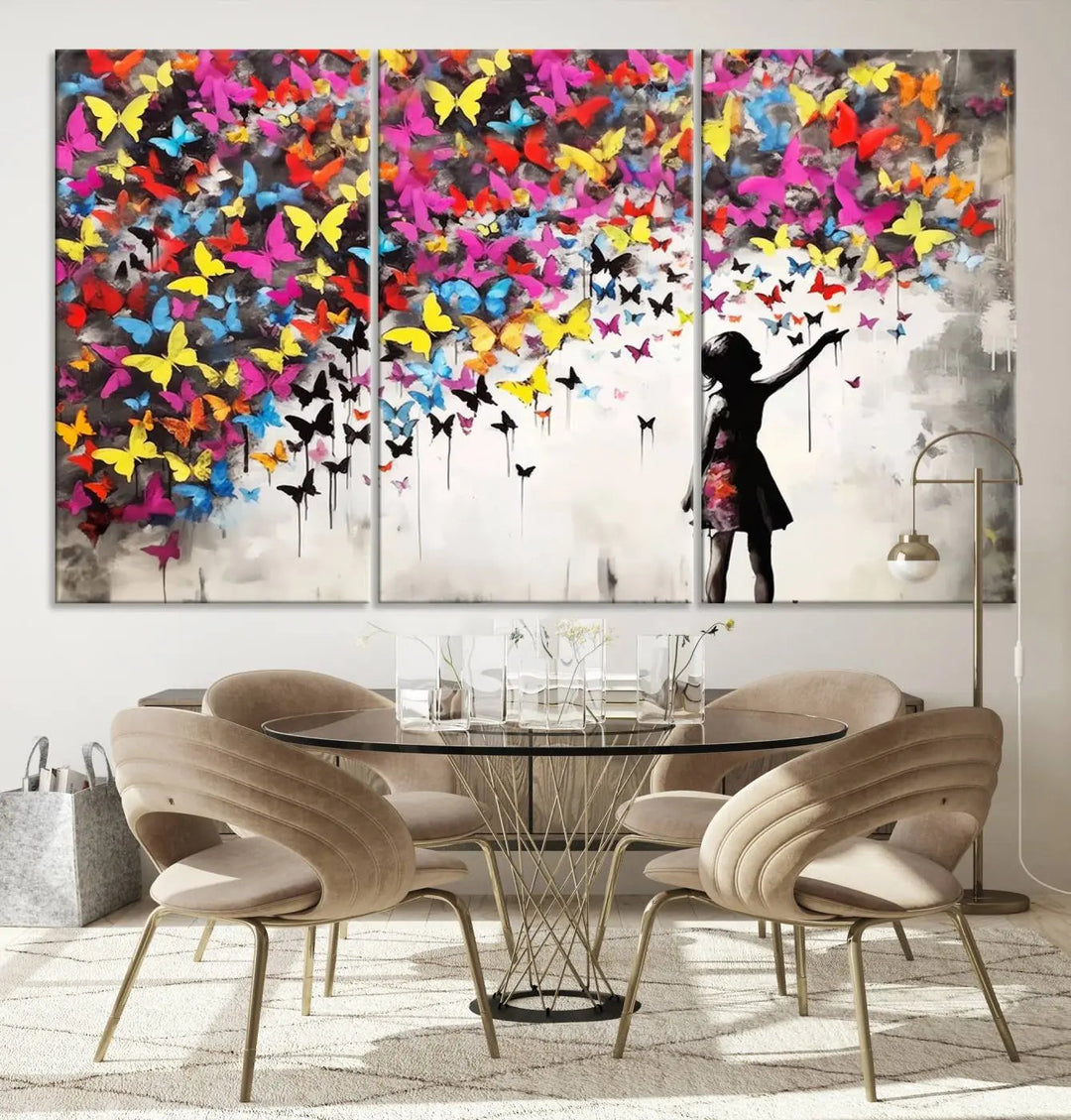 The Banksy Style Wall Art - Girl and Butterfly Explosion features a silhouette of a girl reaching for colorful butterflies on a three-panel canvas print.