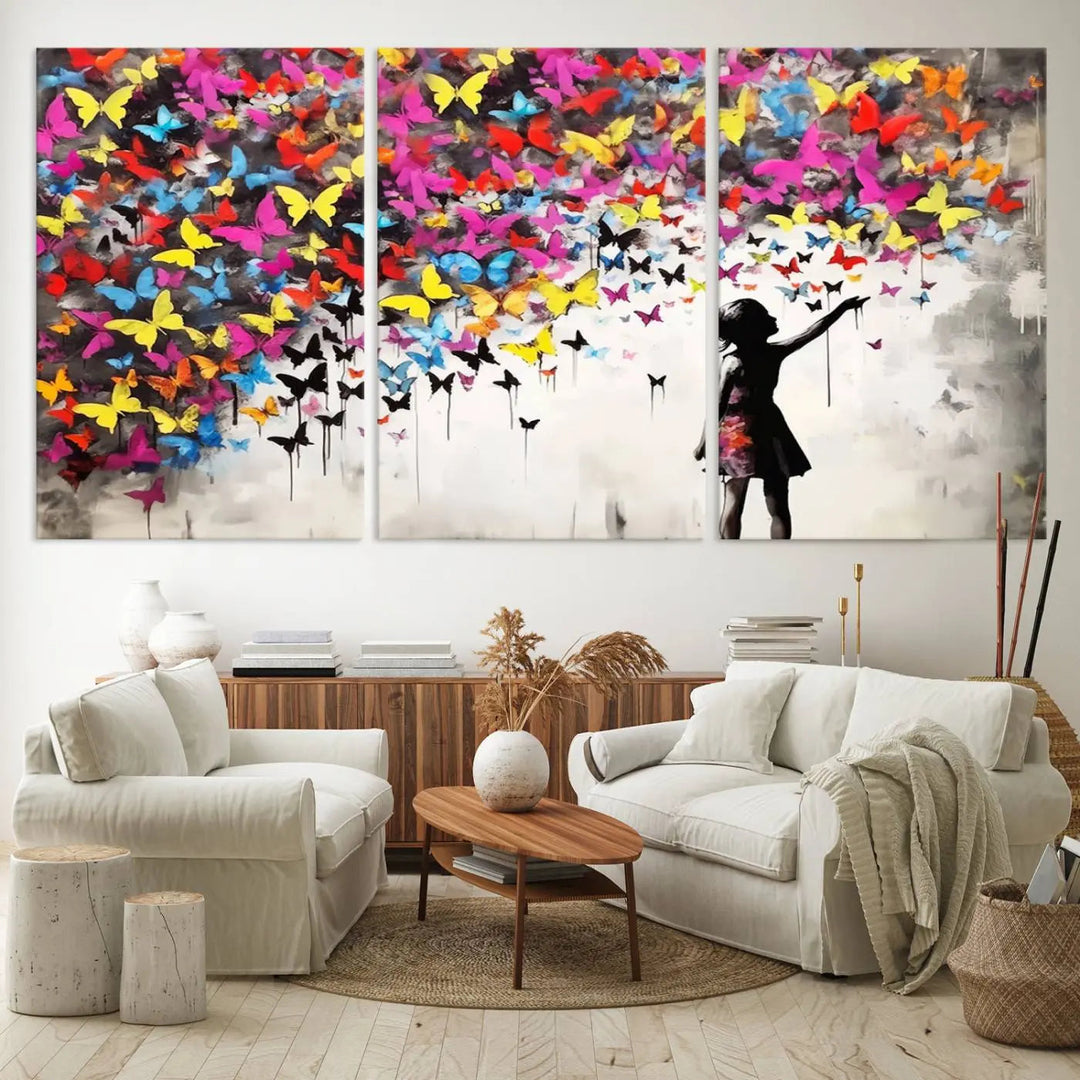 The Banksy Style Wall Art - Girl and Butterfly Explosion features a silhouette of a girl reaching for colorful butterflies on a three-panel canvas print.