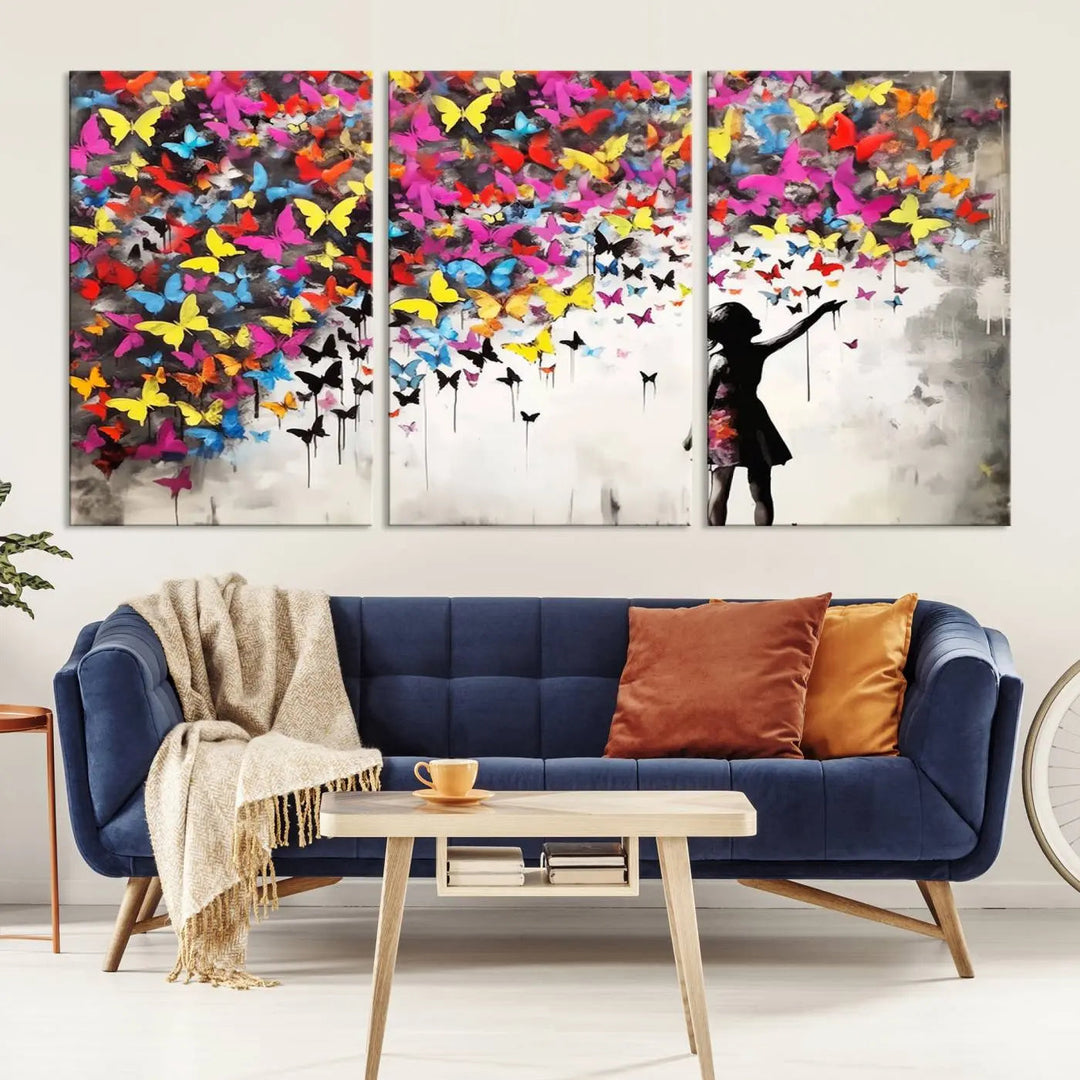 The Banksy Style Wall Art - Girl and Butterfly Explosion features a silhouette of a girl reaching for colorful butterflies on a three-panel canvas print.