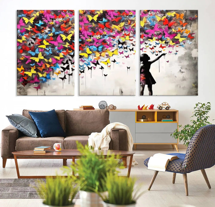 The Banksy Style Wall Art - Girl and Butterfly Explosion features a silhouette of a girl reaching for colorful butterflies on a three-panel canvas print.