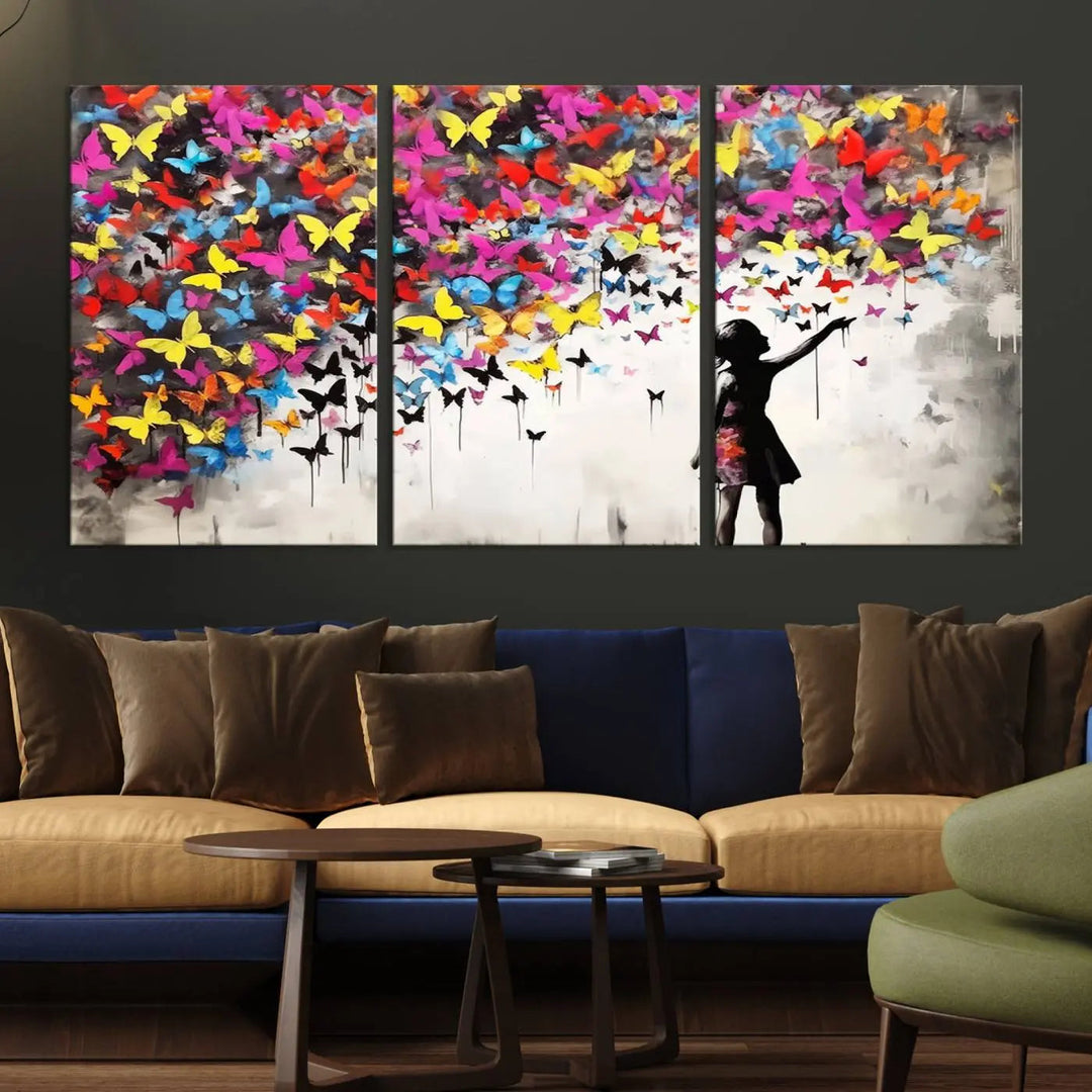 The Banksy Style Wall Art - Girl and Butterfly Explosion features a silhouette of a girl reaching for colorful butterflies on a three-panel canvas print.