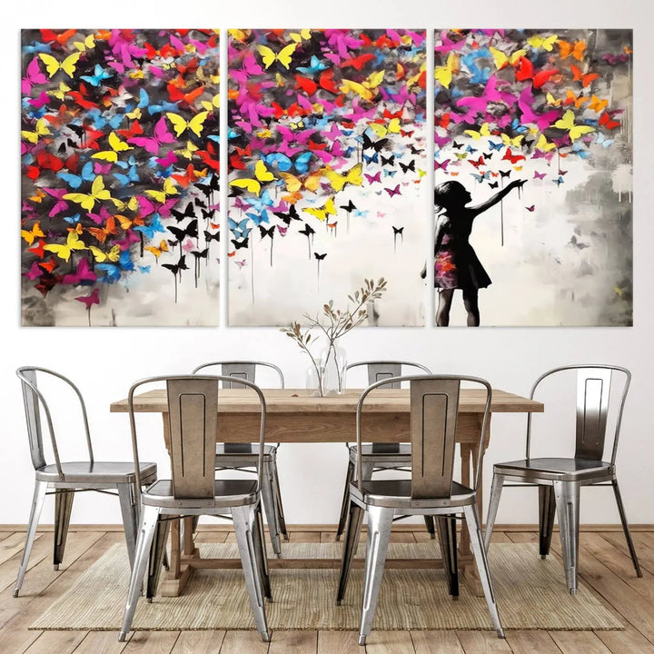 The Banksy Style Wall Art - Girl and Butterfly Explosion features a silhouette of a girl reaching for colorful butterflies on a three-panel canvas print.