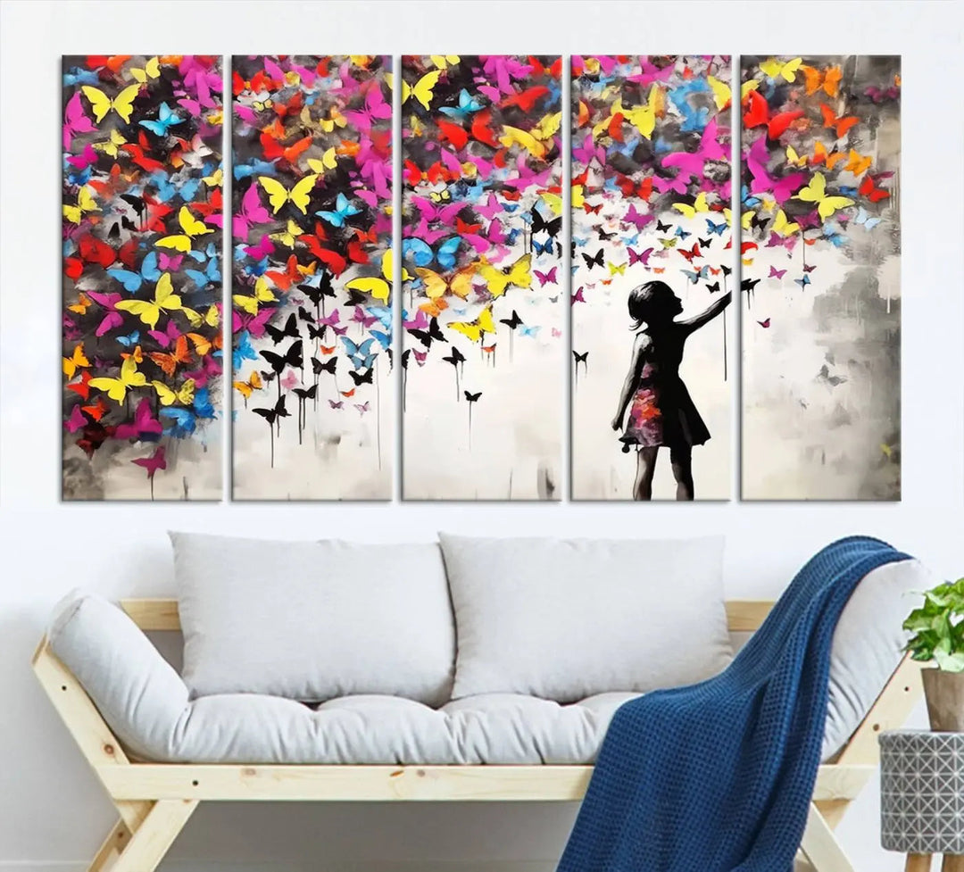 The Banksy Style Wall Art - Girl and Butterfly Explosion features a silhouette of a girl reaching for colorful butterflies on a three-panel canvas print.