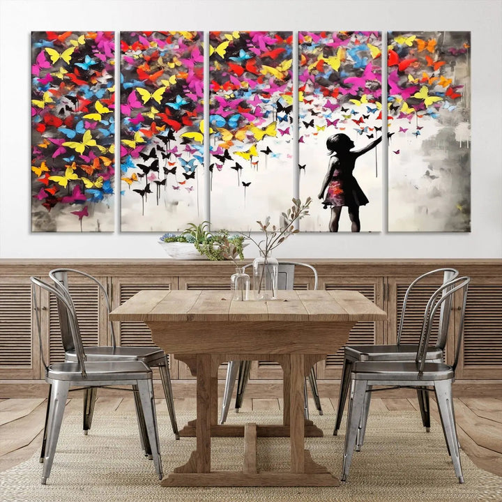 The Banksy Style Wall Art - Girl and Butterfly Explosion features a silhouette of a girl reaching for colorful butterflies on a three-panel canvas print.