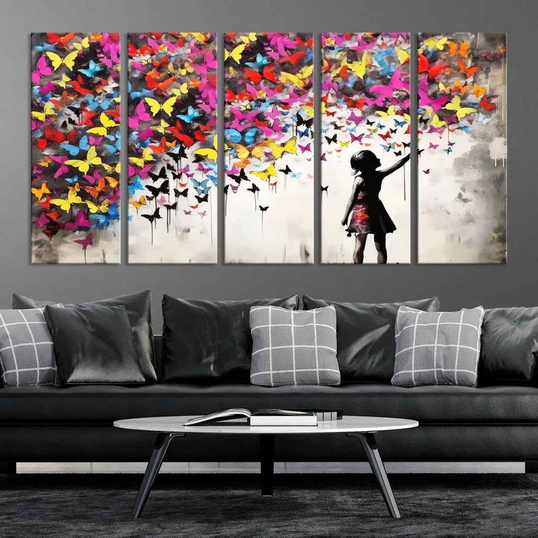 The Banksy Style Wall Art - Girl and Butterfly Explosion features a silhouette of a girl reaching for colorful butterflies on a three-panel canvas print.