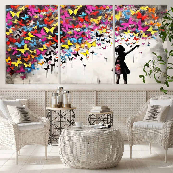 The Banksy Style Wall Art - Girl and Butterfly Explosion features a silhouette of a girl reaching for colorful butterflies on a three-panel canvas print.