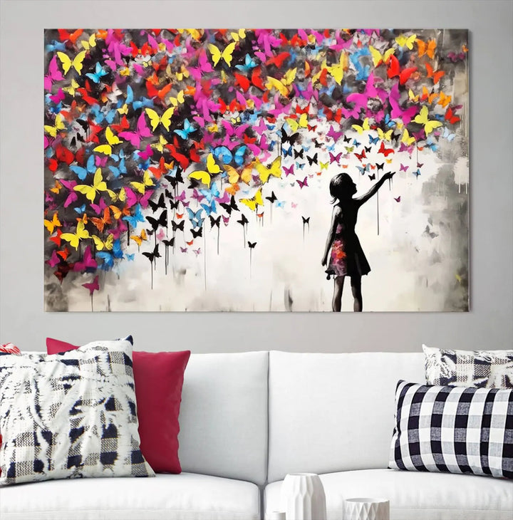 The Banksy Style Wall Art - Girl and Butterfly Explosion features a silhouette of a girl reaching for colorful butterflies on a three-panel canvas print.