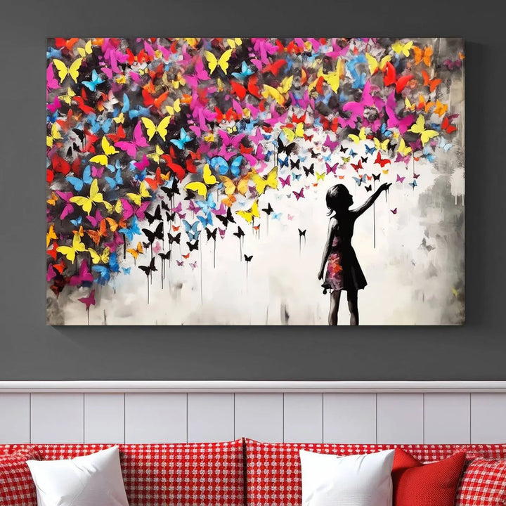 The Banksy Style Wall Art - Girl and Butterfly Explosion features a silhouette of a girl reaching for colorful butterflies on a three-panel canvas print.