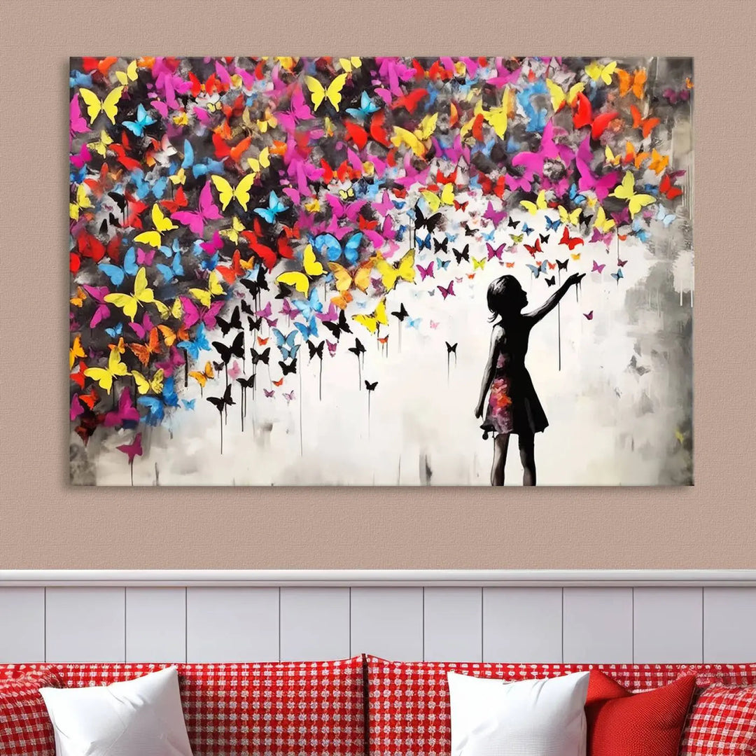 The Banksy Style Wall Art - Girl and Butterfly Explosion features a silhouette of a girl reaching for colorful butterflies on a three-panel canvas print.