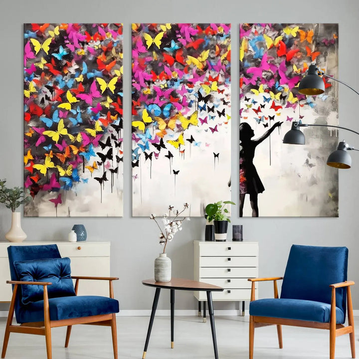 The Banksy Style Wall Art - Girl and Butterfly Explosion features a silhouette of a girl reaching for colorful butterflies on a three-panel canvas print.