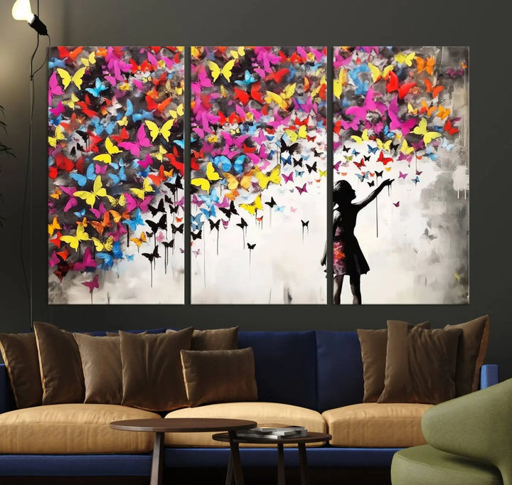 The Banksy Style Wall Art - Girl and Butterfly Explosion features a silhouette of a girl reaching for colorful butterflies on a three-panel canvas print.