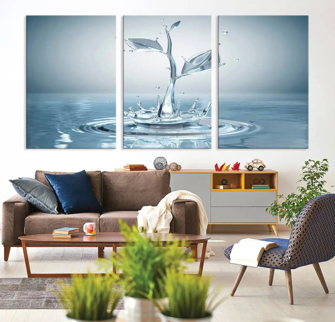 The living room features a three-panel wall art titled "Bathroom Wall Art Blue Leaf Canvas," showcasing water splash shapes that form plant-like designs on gallery-wrapped, museum-quality canvas.