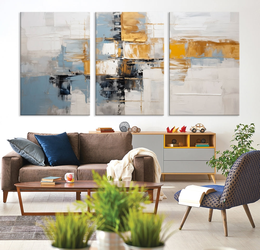 A stunning triptych of the Blue Orange Abstract Wall Art Canvas Print adorns the wall. These gallery-wrapped abstract pieces, showcasing blue, yellow, and white tones, feature a UV-protective coating to maintain their vivid colors.