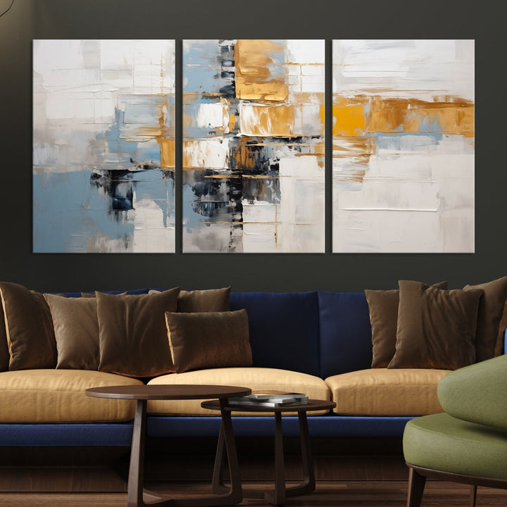 A stunning triptych of the Blue Orange Abstract Wall Art Canvas Print adorns the wall. These gallery-wrapped abstract pieces, showcasing blue, yellow, and white tones, feature a UV-protective coating to maintain their vivid colors.