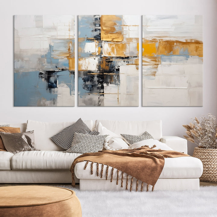 A stunning triptych of the Blue Orange Abstract Wall Art Canvas Print adorns the wall. These gallery-wrapped abstract pieces, showcasing blue, yellow, and white tones, feature a UV-protective coating to maintain their vivid colors.