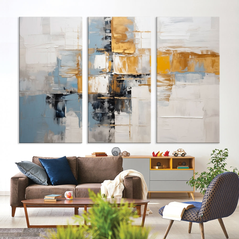 A stunning triptych of the Blue Orange Abstract Wall Art Canvas Print adorns the wall. These gallery-wrapped abstract pieces, showcasing blue, yellow, and white tones, feature a UV-protective coating to maintain their vivid colors.