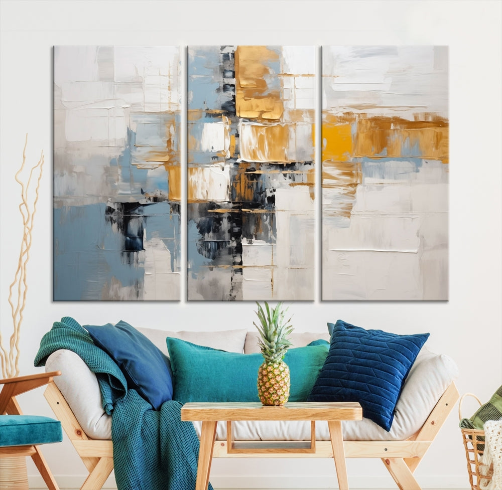 A stunning triptych of the Blue Orange Abstract Wall Art Canvas Print adorns the wall. These gallery-wrapped abstract pieces, showcasing blue, yellow, and white tones, feature a UV-protective coating to maintain their vivid colors.