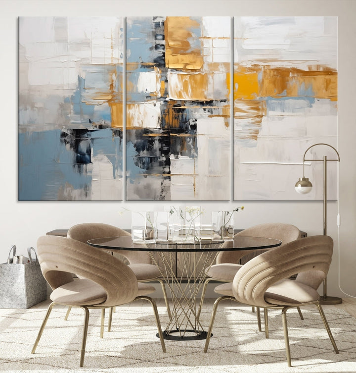 A stunning triptych of the Blue Orange Abstract Wall Art Canvas Print adorns the wall. These gallery-wrapped abstract pieces, showcasing blue, yellow, and white tones, feature a UV-protective coating to maintain their vivid colors.