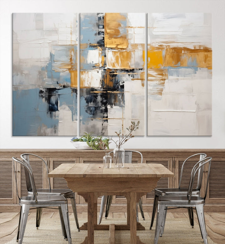 A stunning triptych of the Blue Orange Abstract Wall Art Canvas Print adorns the wall. These gallery-wrapped abstract pieces, showcasing blue, yellow, and white tones, feature a UV-protective coating to maintain their vivid colors.