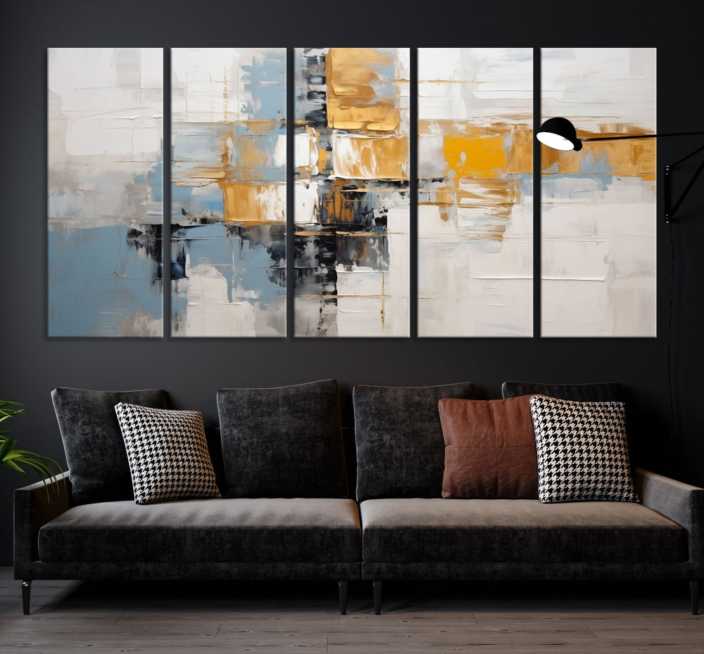 A stunning triptych of the Blue Orange Abstract Wall Art Canvas Print adorns the wall. These gallery-wrapped abstract pieces, showcasing blue, yellow, and white tones, feature a UV-protective coating to maintain their vivid colors.