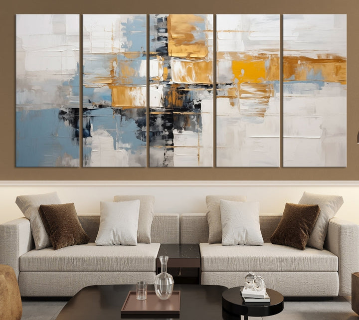 A stunning triptych of the Blue Orange Abstract Wall Art Canvas Print adorns the wall. These gallery-wrapped abstract pieces, showcasing blue, yellow, and white tones, feature a UV-protective coating to maintain their vivid colors.