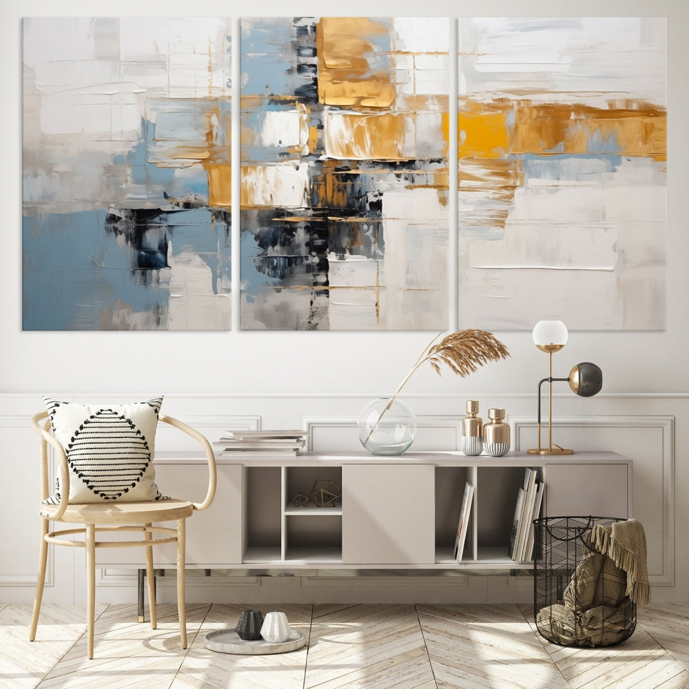 A stunning triptych of the Blue Orange Abstract Wall Art Canvas Print adorns the wall. These gallery-wrapped abstract pieces, showcasing blue, yellow, and white tones, feature a UV-protective coating to maintain their vivid colors.