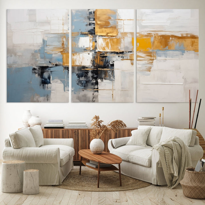 A stunning triptych of the Blue Orange Abstract Wall Art Canvas Print adorns the wall. These gallery-wrapped abstract pieces, showcasing blue, yellow, and white tones, feature a UV-protective coating to maintain their vivid colors.