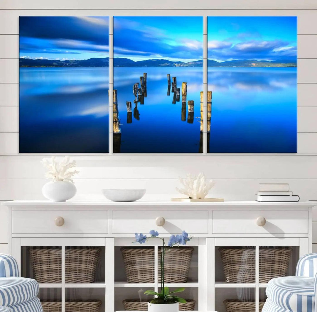 The Calm Waters Lake Canvas Art, featuring a tranquil pier reflection set against a mountainous backdrop, showcases its elegance with a gallery wrap and Canon print quality.