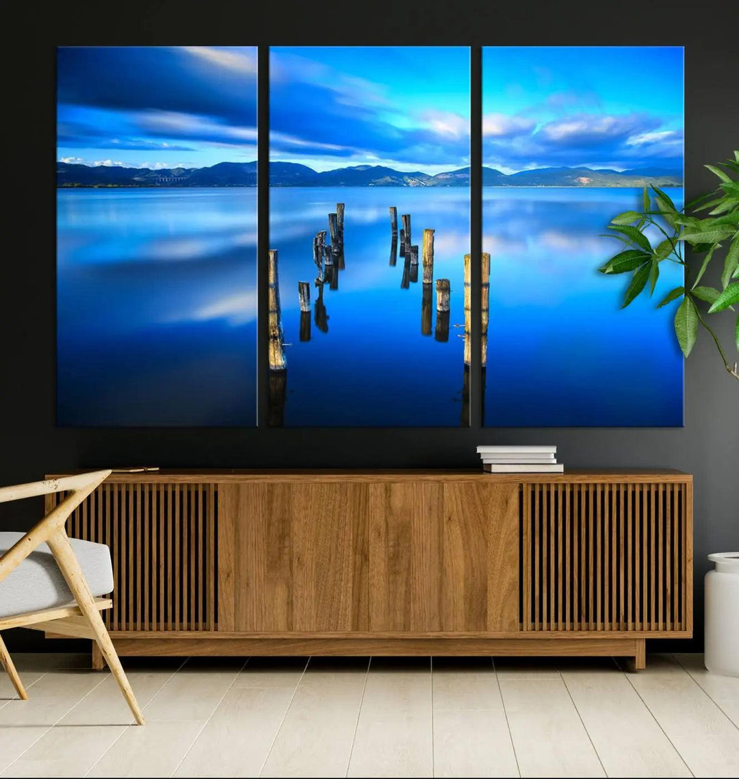 The Calm Waters Lake Canvas Art, featuring a tranquil pier reflection set against a mountainous backdrop, showcases its elegance with a gallery wrap and Canon print quality.