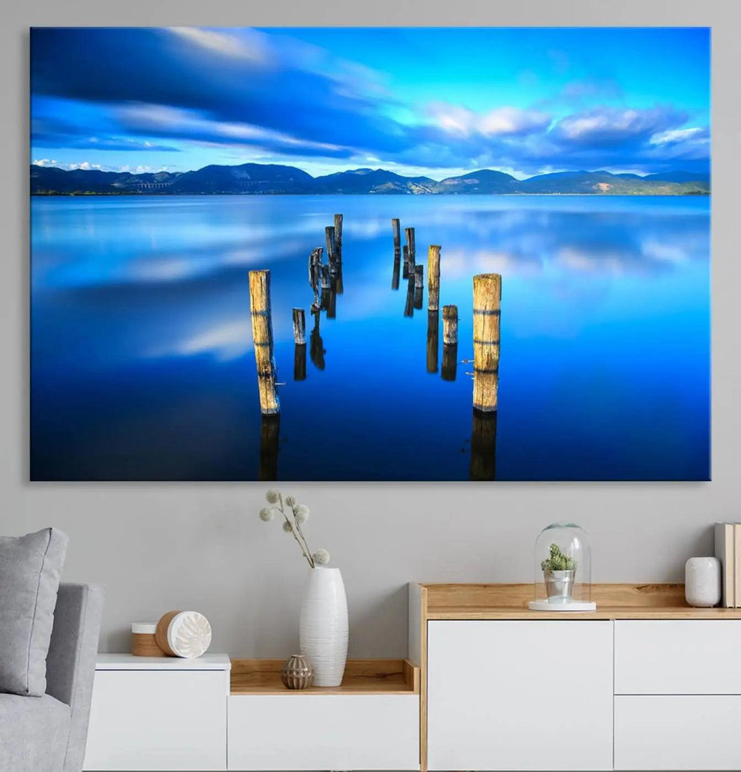 The Calm Waters Lake Canvas Art, featuring a tranquil pier reflection set against a mountainous backdrop, showcases its elegance with a gallery wrap and Canon print quality.