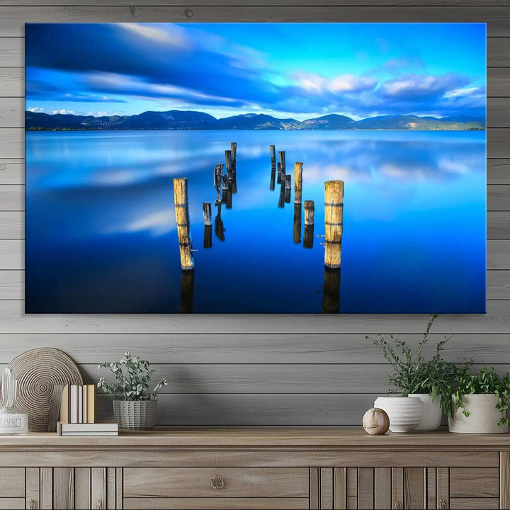 The Calm Waters Lake Canvas Art, featuring a tranquil pier reflection set against a mountainous backdrop, showcases its elegance with a gallery wrap and Canon print quality.