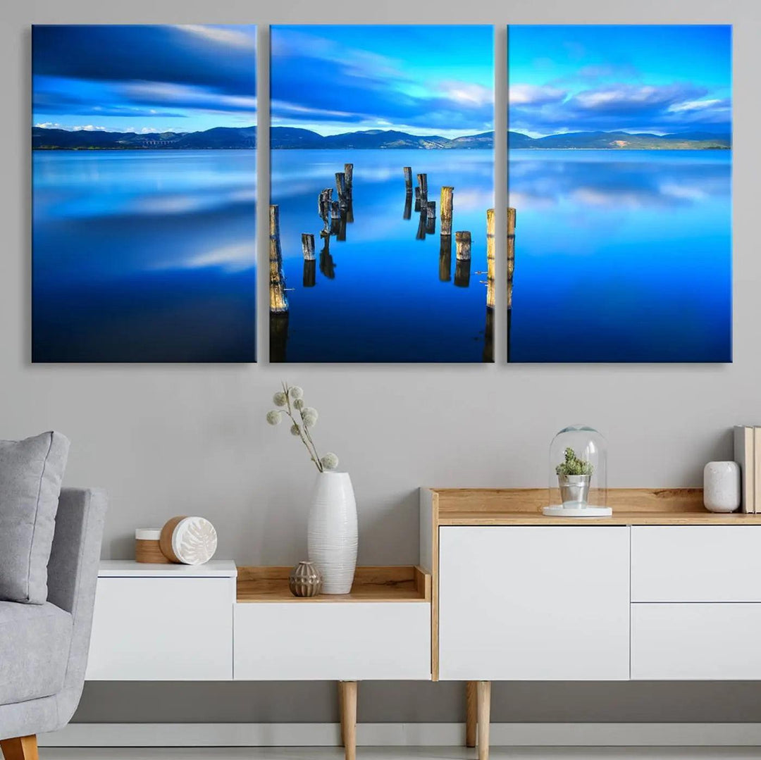 The Calm Waters Lake Canvas Art, featuring a tranquil pier reflection set against a mountainous backdrop, showcases its elegance with a gallery wrap and Canon print quality.