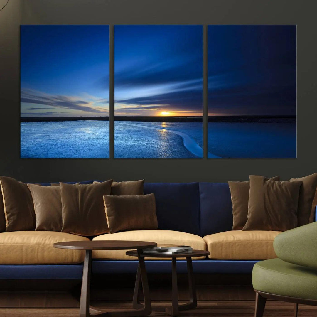 The serene living room is highlighted by the Deep Blue Ocean Sunset Triptych Canvas Art—a striking and serene coastal sunset print featuring an ocean horizon and sunset theme—commanding attention on the wall.