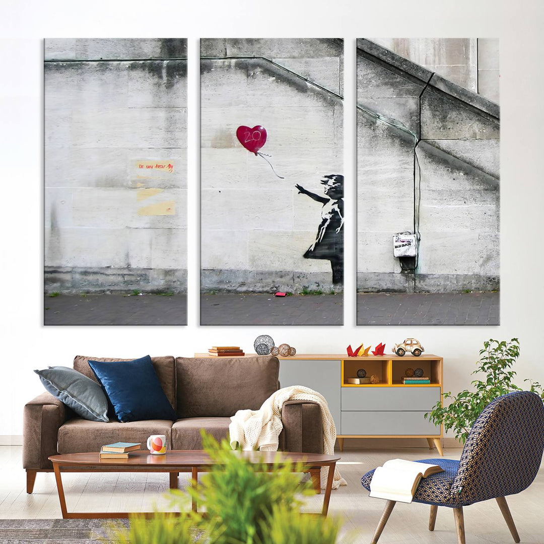 The "Girl with a Balloon Banksy Street Graffiti Art Canvas Print" is a gallery-quality wall art piece that features an image of a girl releasing a heart-shaped balloon. Handmade in the USA, this canvas artwork brings charm and emotion to any room.