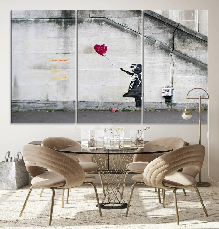 The "Girl with a Balloon Banksy Street Graffiti Art Canvas Print" is a gallery-quality wall art piece that features an image of a girl releasing a heart-shaped balloon. Handmade in the USA, this canvas artwork brings charm and emotion to any room.