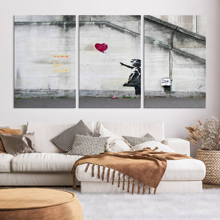 The "Girl with a Balloon Banksy Street Graffiti Art Canvas Print" is a gallery-quality wall art piece that features an image of a girl releasing a heart-shaped balloon. Handmade in the USA, this canvas artwork brings charm and emotion to any room.