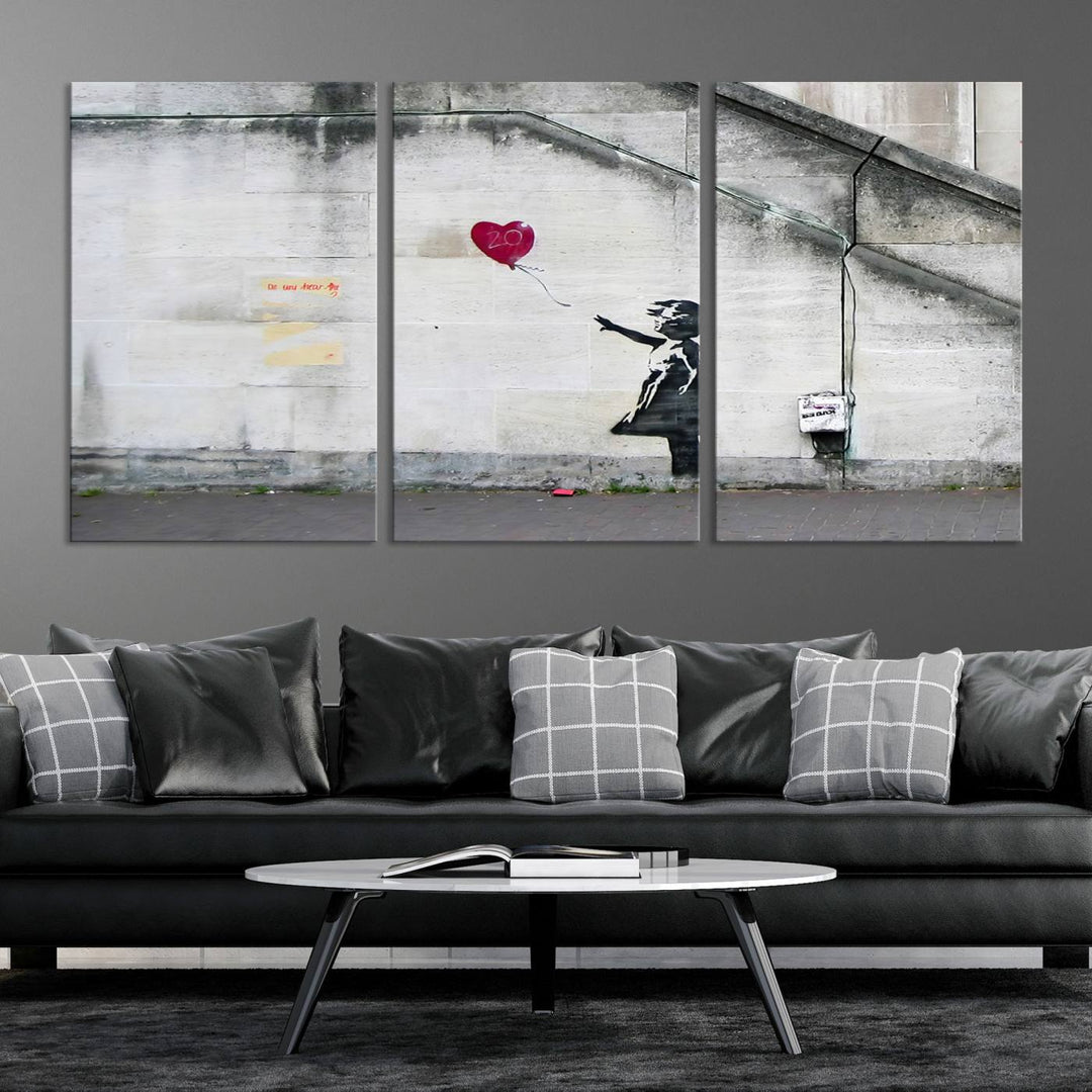 The "Girl with a Balloon Banksy Street Graffiti Art Canvas Print" is a gallery-quality wall art piece that features an image of a girl releasing a heart-shaped balloon. Handmade in the USA, this canvas artwork brings charm and emotion to any room.