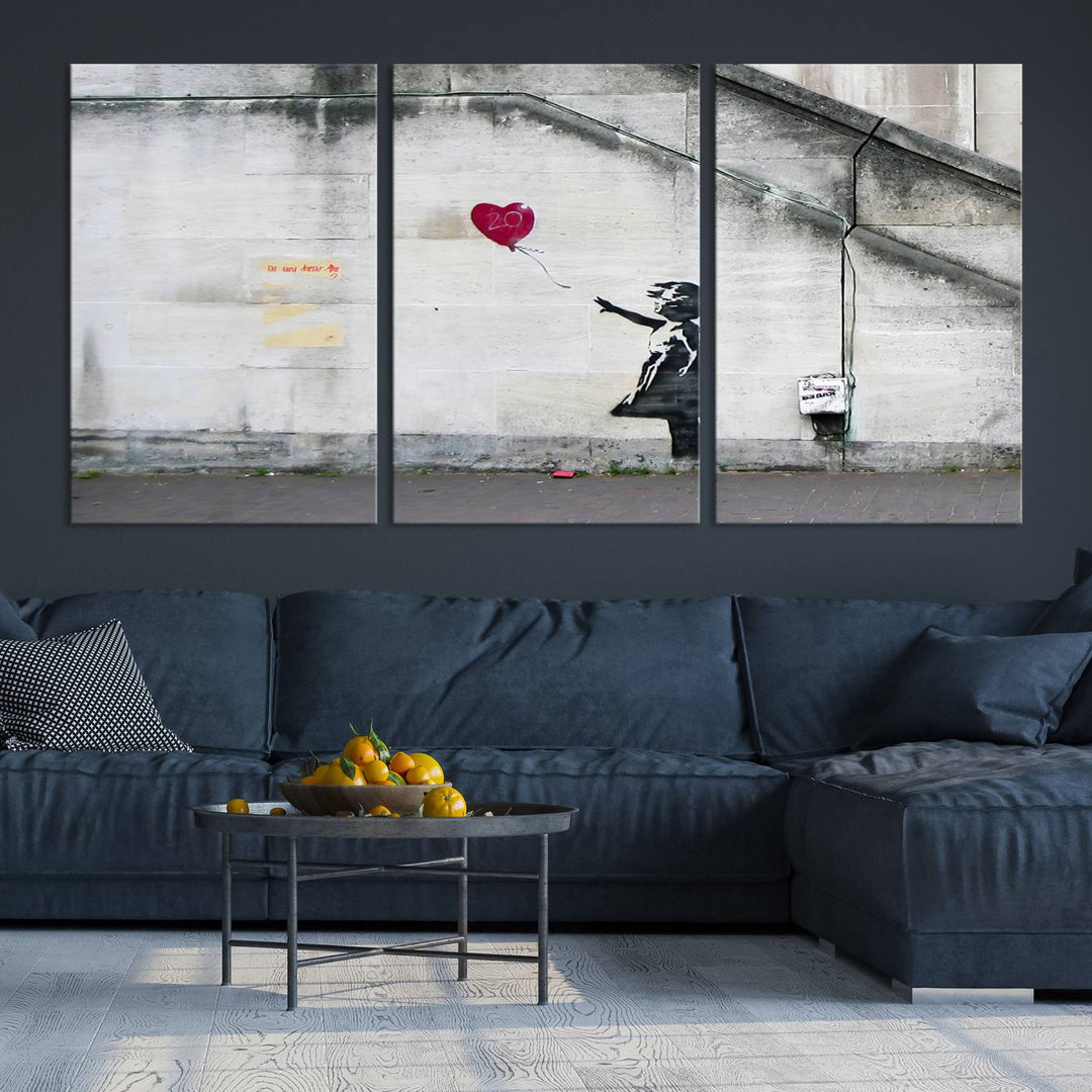 The "Girl with a Balloon Banksy Street Graffiti Art Canvas Print" is a gallery-quality wall art piece that features an image of a girl releasing a heart-shaped balloon. Handmade in the USA, this canvas artwork brings charm and emotion to any room.