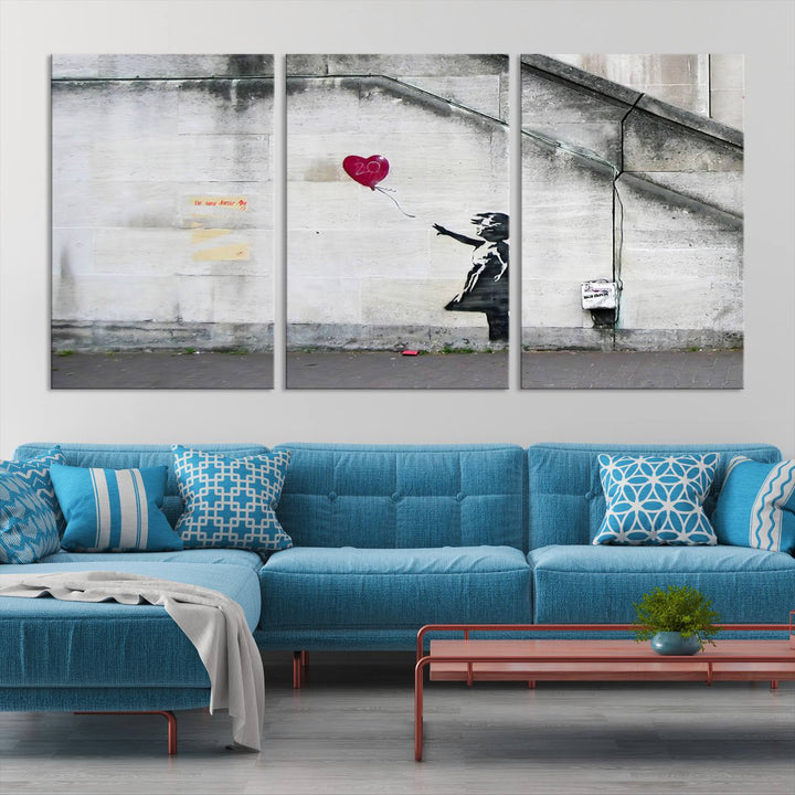 The "Girl with a Balloon Banksy Street Graffiti Art Canvas Print" is a gallery-quality wall art piece that features an image of a girl releasing a heart-shaped balloon. Handmade in the USA, this canvas artwork brings charm and emotion to any room.