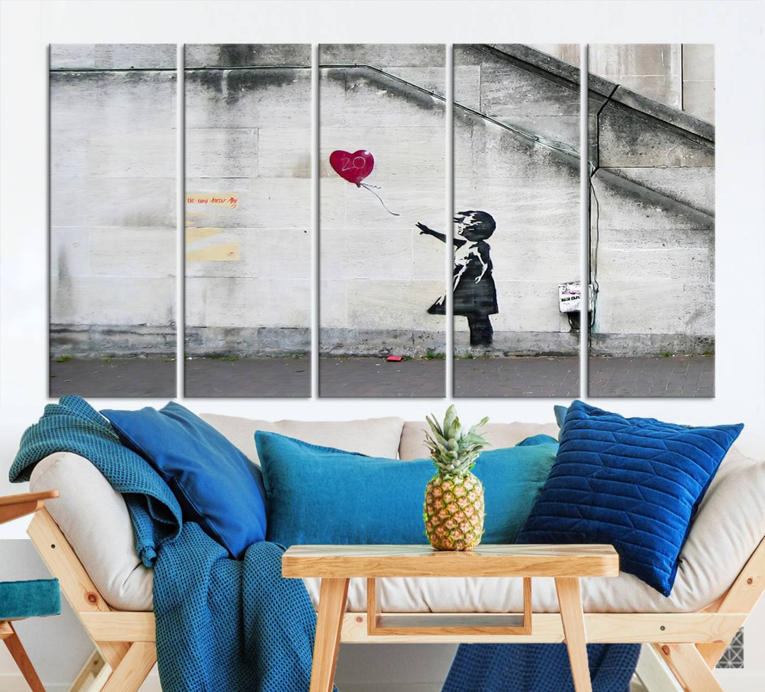 The "Girl with a Balloon Banksy Street Graffiti Art Canvas Print" is a gallery-quality wall art piece that features an image of a girl releasing a heart-shaped balloon. Handmade in the USA, this canvas artwork brings charm and emotion to any room.