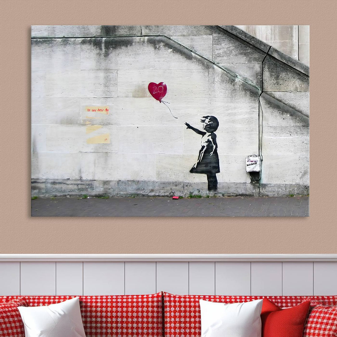 The "Girl with a Balloon Banksy Street Graffiti Art Canvas Print" is a gallery-quality wall art piece that features an image of a girl releasing a heart-shaped balloon. Handmade in the USA, this canvas artwork brings charm and emotion to any room.