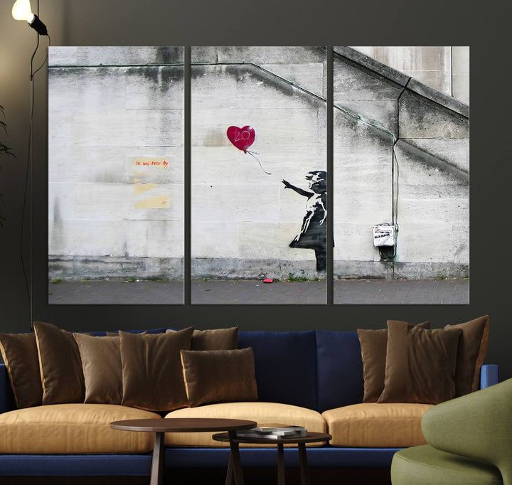 The "Girl with a Balloon Banksy Street Graffiti Art Canvas Print" is a gallery-quality wall art piece that features an image of a girl releasing a heart-shaped balloon. Handmade in the USA, this canvas artwork brings charm and emotion to any room.