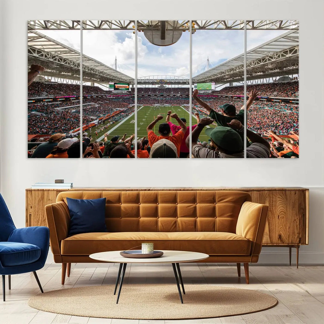 The living room features handmade triptych wall art crafted in the USA, depicting a cheering crowd at a Miami Hurricanes football game. The artwork showcases the Miami Hard Rock Stadium on premium canvas.