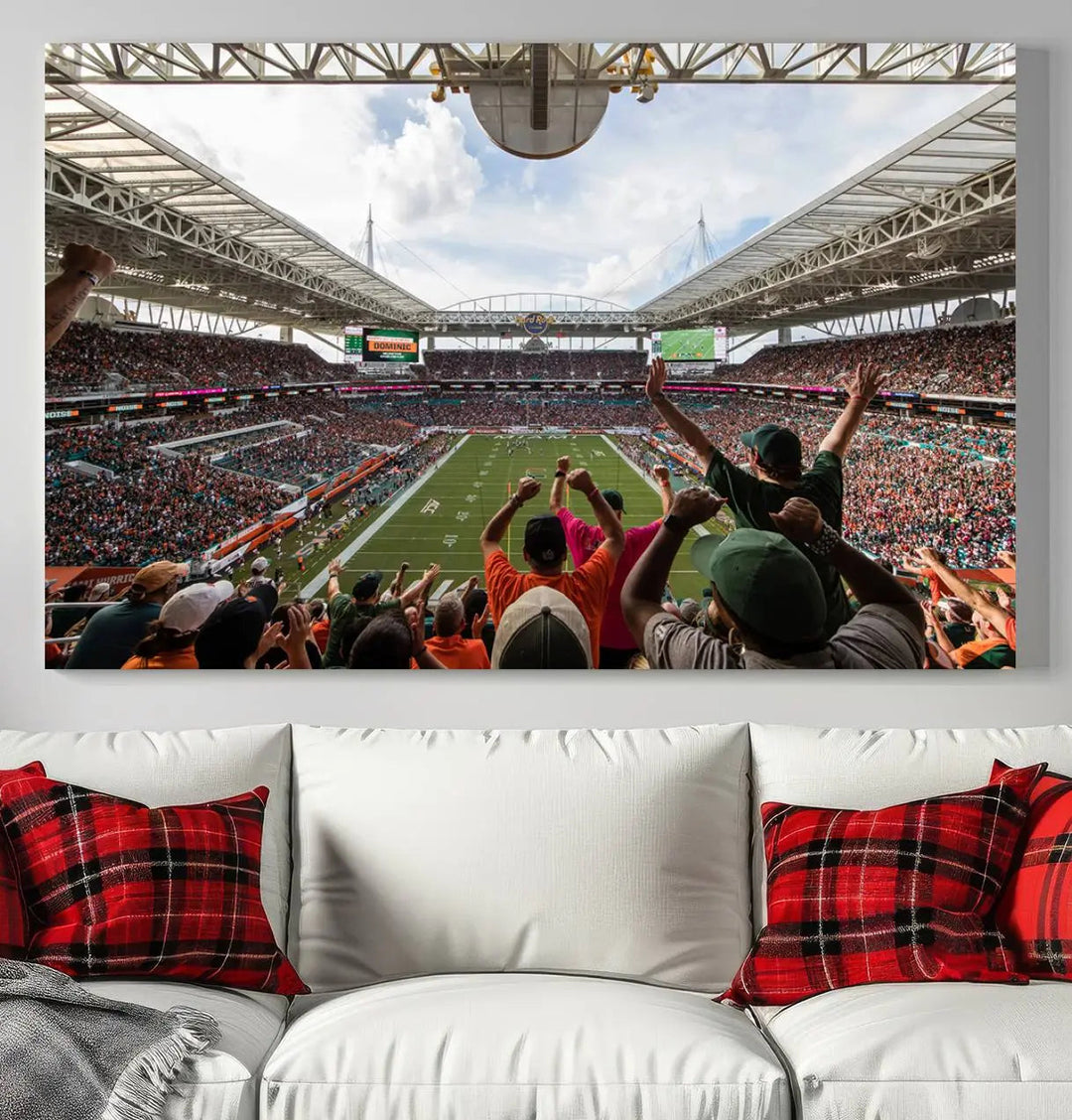 The living room features handmade triptych wall art crafted in the USA, depicting a cheering crowd at a Miami Hurricanes football game. The artwork showcases the Miami Hard Rock Stadium on premium canvas.