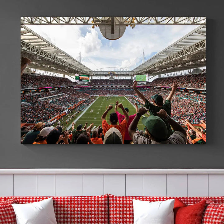 The living room features handmade triptych wall art crafted in the USA, depicting a cheering crowd at a Miami Hurricanes football game. The artwork showcases the Miami Hard Rock Stadium on premium canvas.