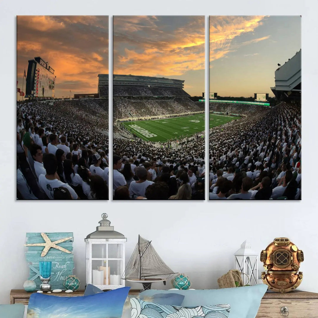 A living room showcasing a stunning Michigan State Spartans Football Team Print on a three-panel canvas, depicting the bustling Spartan Stadium in East Lansing at sunset, all handmade in the USA.