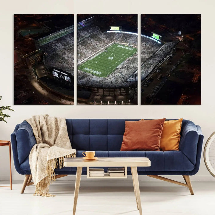 The "Michigan State Spartans Football Team Print - East Lansing Spartan Stadium Wall Art Canvas Print" is elegantly displayed on a wall, showcasing a brightly lit football stadium at night with a gallery-quality finish.