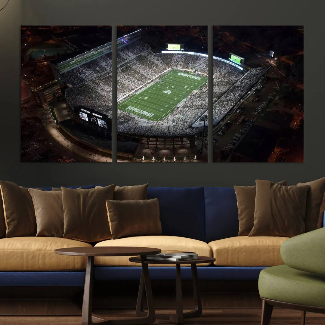 The "Michigan State Spartans Football Team Print - East Lansing Spartan Stadium Wall Art Canvas Print" is elegantly displayed on a wall, showcasing a brightly lit football stadium at night with a gallery-quality finish.