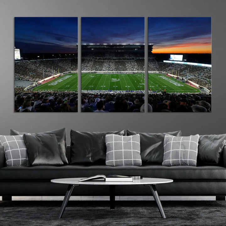 The room showcases a triptych wall art featuring the Michigan State Spartans football team at East Lansing Spartan Stadium at dusk, elegantly printed on premium canvas for a gallery-quality finish.