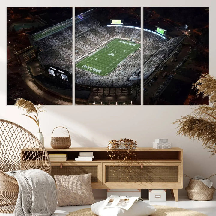 The "Michigan State Spartans Football Team Print - East Lansing Spartan Stadium Wall Art Canvas Print" is elegantly displayed on a wall, showcasing a brightly lit football stadium at night with a gallery-quality finish.